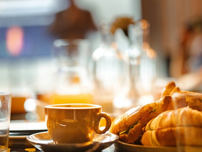 Breakfast plate with eggs, sausage, and coffee on a wooden table